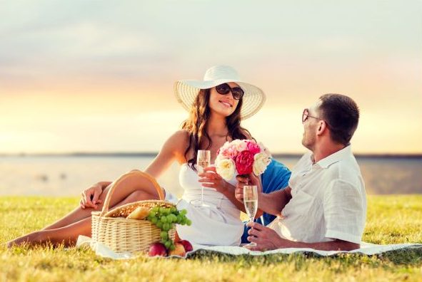 47564042 - love, dating, people and holidays concept - smiling couple drinking champagne on picnic over evening seaside background
