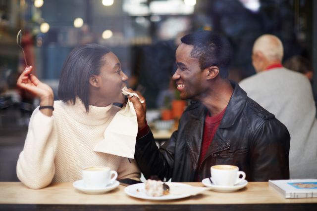 47489911 - portrait of young couple in love at a coffee shop, boyfriend wiping her mouth with a napkin at breakfast, romantic couple having fun together, two friends smiling sitting in cafe